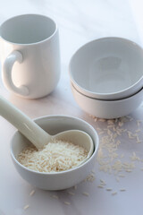 High key white rice in bowl with cup and spoon.