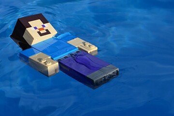 Obraz premium LEGO Minecraft figure of Steve swimming backstroke in swimming pool with azure blue floor.