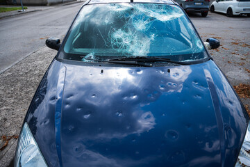 hail damage to car. damaged hood and windshield - obrazy, fototapety, plakaty