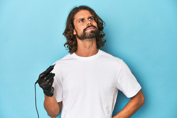 Bearded tattooist with tattoo machine at work dreaming of achieving goals and purposes