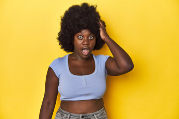 African-American woman with afro, studio yellow background being shocked, she has remembered...