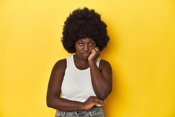 Fototapeta na wymiar African-American woman with afro, studio yellow background who is bored, fatigued and need a relax day.
