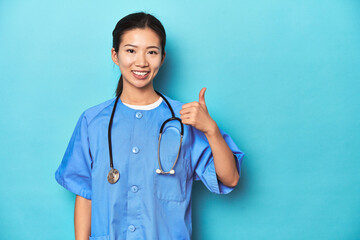 Asian nurse with stethoscope, medical studio shot, smiling and raising thumb up