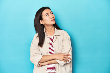 Fototapeta premium Asian woman in layered shirt and striped t-shirt, dreaming of achieving goals and purposes