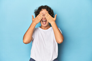 Young Caucasian woman with short hair covers eyes with hands, smiles broadly waiting for a surprise.