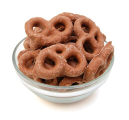 Several milk chocolate covered pretzels in glass bowl on white