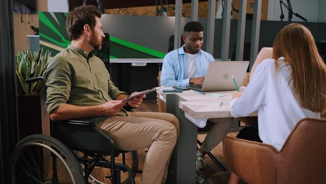 Young manager in wheelchair conducts meeting in office