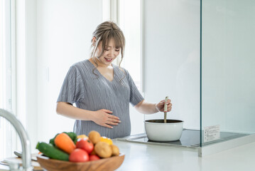 キッチンで料理をするアジア人女性・妊婦・プレママ（胎動）
