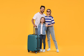 Fototapeta na wymiar Happy family with green suitcase on orange background