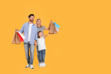Family shopping. Happy parents and daughter with paper bags on orange background. Space for text