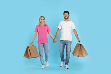 Family shopping. Happy couple with many paper bags on light blue background