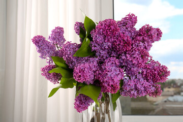 Beautiful lilac flowers in vase near window indoors