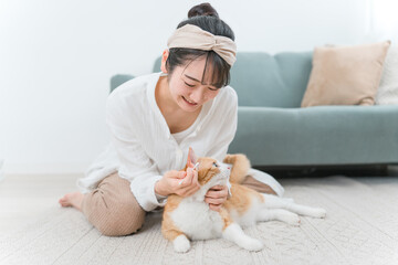 綿棒を使って猫の耳掃除をする飼い主のアジア人女性
