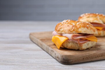 Delicious bagels with ham and cheese on light wooden table. Space for text