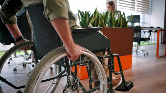Man in wheelchair moves down corridor in open office space