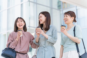コーヒーを持ちながら話すアジア人女性（同僚、ママ友、女友達）
