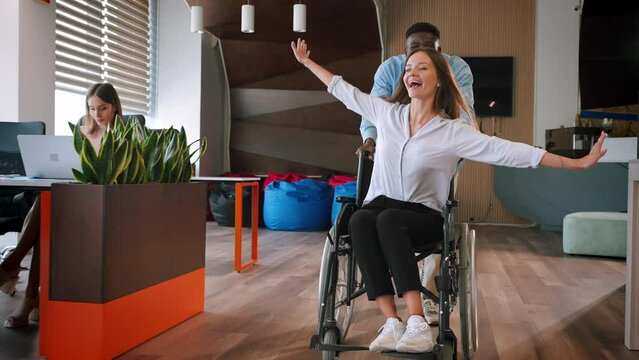 African American man runs pushing lady colleague in wheelchair