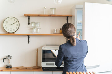 キッチンの電気・冷蔵庫をチェック・点検するビジネスウーマン
