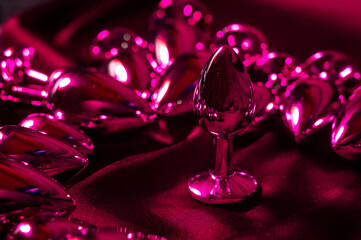 Lots of metal butt plugs in neon pink light. 