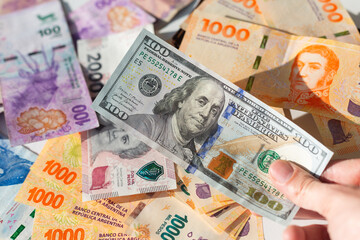 Argentine pesos and dollars. Argentine money banknotes and a hundred Dollars bill. Exchange rate...