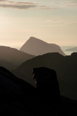 Mountain islands in Norwegian archipelago of Helgeland during sunset. Clouds forming on island mountain peaks at sea. Yellow sunset nordnorge. Dramatic contrast in Norway peaks. Smaltind, Luröy fjell