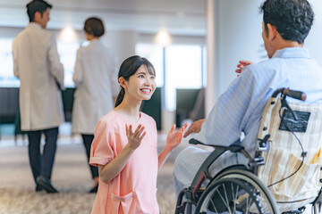 病院で車椅子の患者と会話する看護師