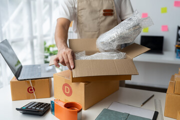 Fototapeta na wymiar Online shopping concept, independent entrepreneur preparing to pack items into parcel boxes for delivery to customers, e-commerce, network delivery. business retail market