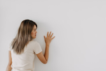Funny asian woman lie on background try to spy and listen over the wall.