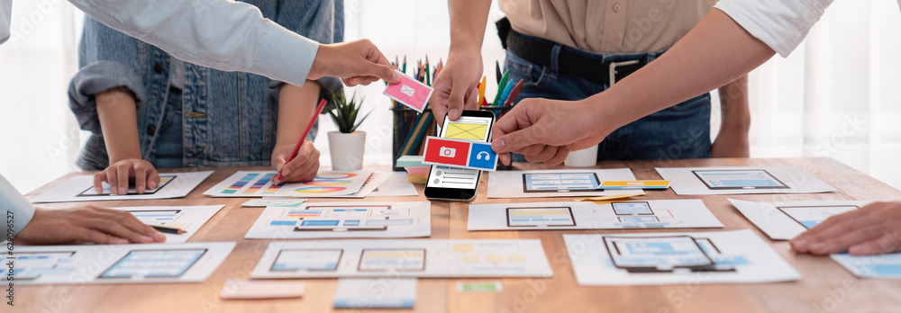 Poster Panorama shot of front-end developer team brainstorming UI and UX designs for mobile app on paper wireframe interface. User interface development team planning for user-friendly UI design. Scrutinize