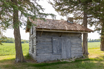 Rural landscape view of a 19th century log cabin on the prairie in midwestern United States