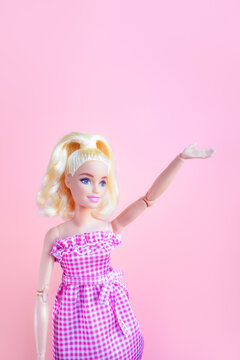 片手を上に挙げるジェスチャーをしているバービー人形 - ガイドや説明する女性のイメージ素材	