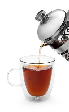 Pouring hot tea from tea kettle to glass cup. Isolated on white.