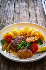 Seared pork meatballs with boiled potatoes and sauerkraut on wooden table
