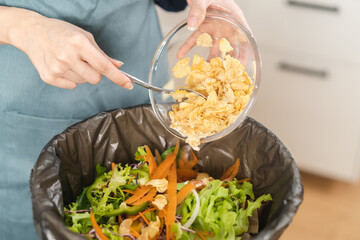 Compost the kitchen waste, recycling, organic meal asian young household woman use spoon scraping, throwing food leftovers into garbage, trash bin from vegetable. Environmentally responsible, ecology.