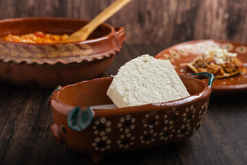 Fresh cheese in clay pot on wood table.