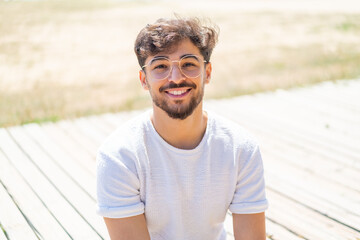 Handsome Arab man at outdoors With glasses with happy expression