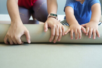 Closeup Asian mother and  little son hands rolling exercise mat after fitness training at home.