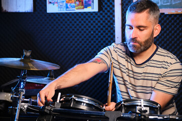 Drummer man adjusting a drum in a drum set in a recording studio. Music production.