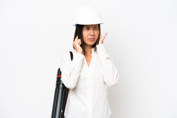 Young architect woman with helmet and holding blueprints isolated on white background frustrated and covering ears