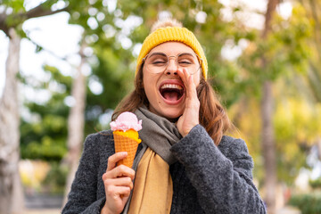 Fototapeta premium Brunette woman with a cornet ice cream at outdoors shouting with mouth wide open