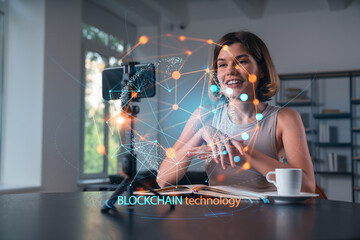 Happy woman is making video blog using smartphone on a tripod explaining with hands at office workplace. Concept of online stream, business education, conference call. Blockchain hologram - Powered by Adobe