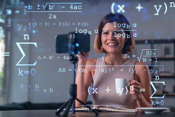 Happy woman is making video blog using smartphone on a tripod explaining with hands at office...