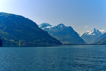 Scenic mountain panorama with Lake Lucerne in the foreground and Swiss village Flüelen in the background on a sunny spring day. Photo taken May 22nd, 2023, Lake Lucerne, Switzerland.