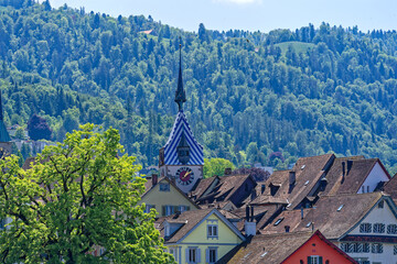 Scenic view of rooftops at the old town of Swiss City of Zug with spire of clock tower and church tower on a sunny spring noon. Photo taken May 22nd, 2023, Zug, Switzerland.