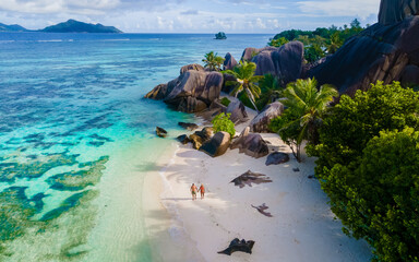 Anse Source d'Argent, La Digue Seychelles, a young couple of men and women on a tropical beach, drone aerial view of a tropical beach at the Seychelles Islands - obrazy, fototapety, plakaty