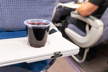 Glass of red wine on table served to passengers in airplane
