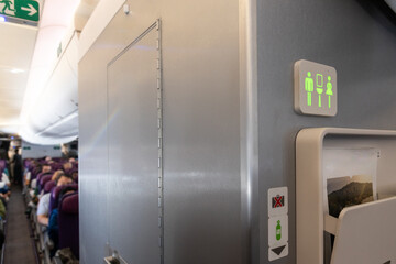Lavatory signage on airplan cabin wall lighted green suggests it is not occupied