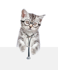 Tabby kitten wearing eyeglasses and with stethoscope on his neck looks above empty white banner. isolated on white background