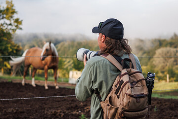 Man photographer with camera photographing horse at ranch