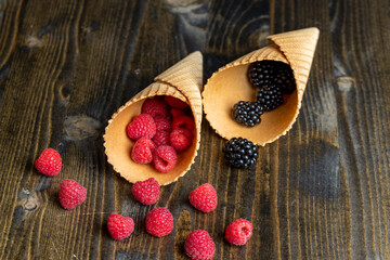 Red ripe raspberries with waffle cups on a black table